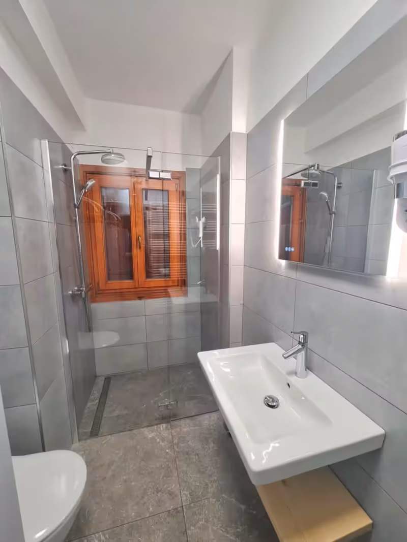 Spodnja kopalnica: prha, umivalnik z osvetljenim ogledalom in stranišče